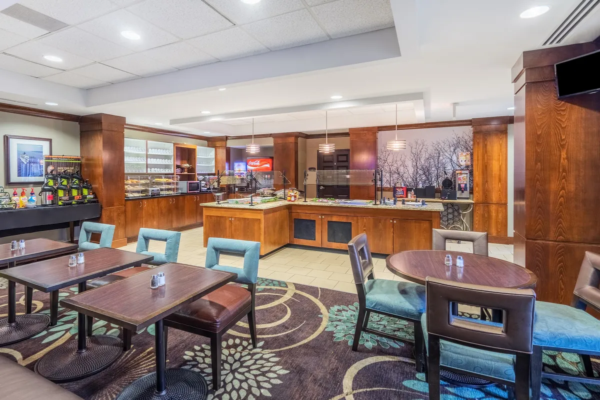 An inviting coffee and snack station with comfortable seating and decorative wall art. The arrangement encourages guests to enjoy snacks, socialize, or unwind in a casual and friendly setting.